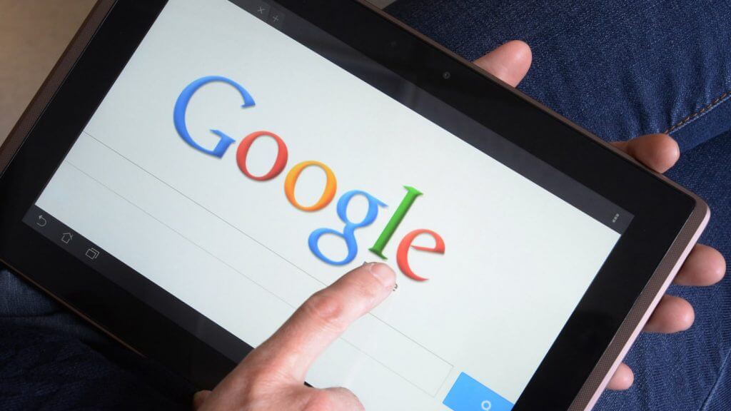 pessoa com um tablet nas mãos utilizando o google para fazer uma pesquisa na web